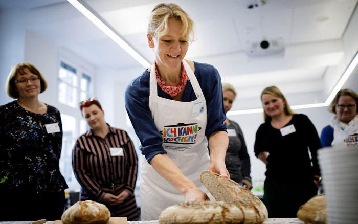 Eine Trainerin schneidet Brot gemeinsam mit Ich kann kochen!-Genussbotschafter:innen im Rahmen einer Fortbildung.